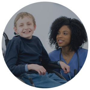 Doctor kneeling beside a smiling youth in wheelchair