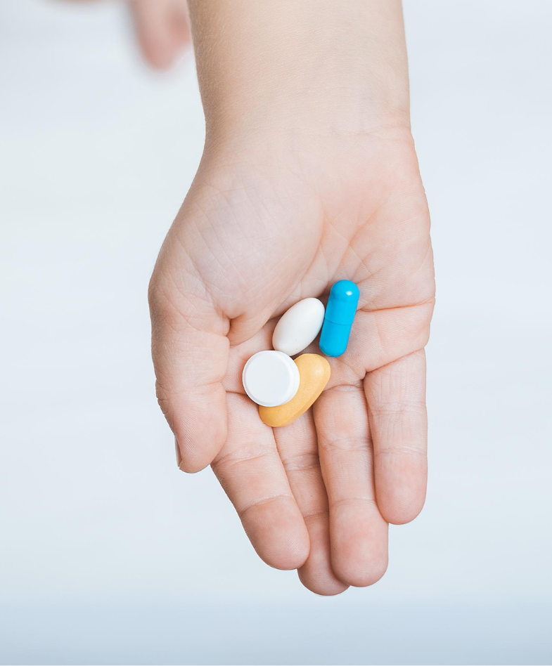 An assortment of pills in the palm of a child's hand.