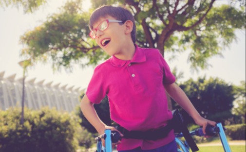 Young boy in pink shirt using walker 