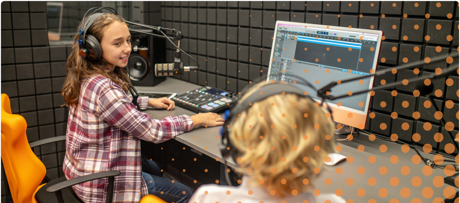 Two children sitting in a podcast recording studio