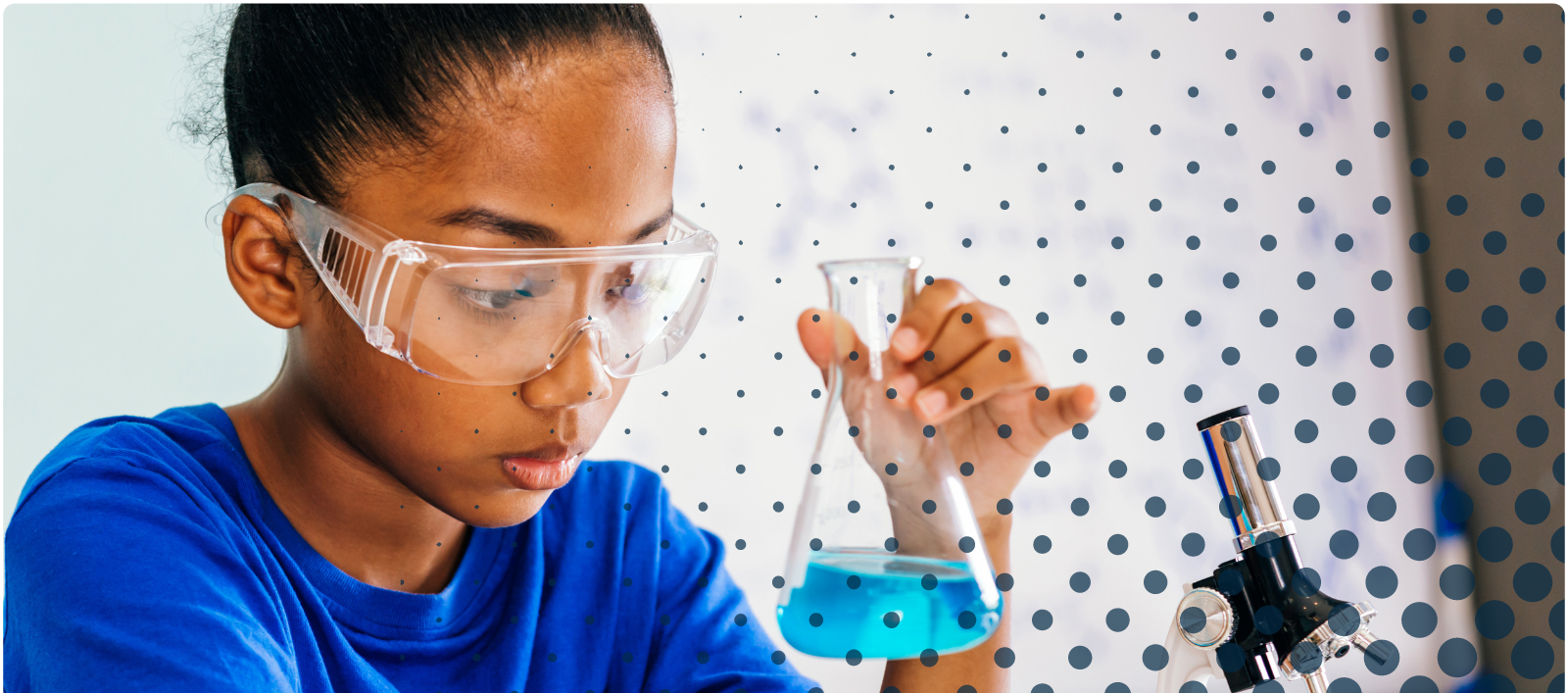 A young girl with safety goggles looking into a beaker with blue liquid inside of it