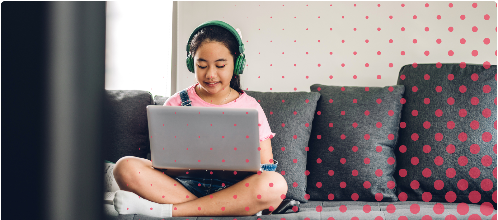 Child sitting on a couch with a laptop on their lap and green headphones on